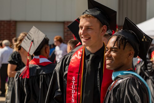 2 students smile after a past commencement ceremony.
