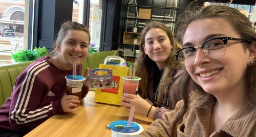 3 young women smile while drinking bubble tea.