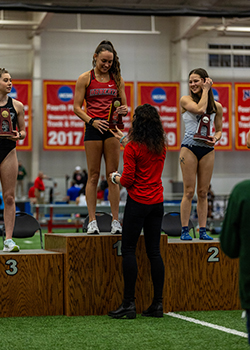 Suhr gives Brynn award while Brynn stands on a podium.