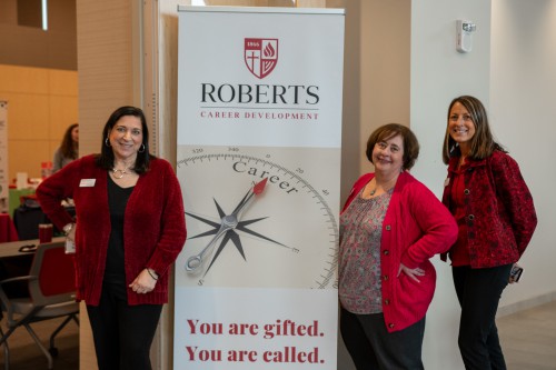 The members of the Career Development office smiles next to their sign