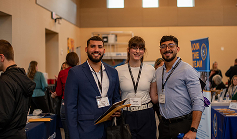 3 students stand and smile