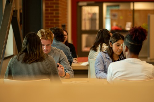 4 students sit around a table and study.