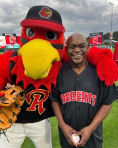 President Hayles smiles next to the Red Wings mascot.