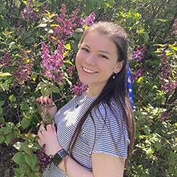 KayLeen Conkinlin smiles in front of flowers