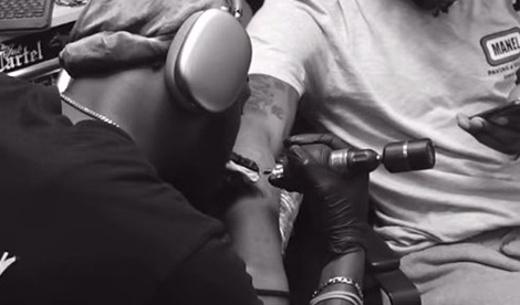 A tattoo artists gives someone a tattoo