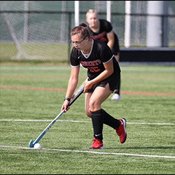 Maddison has the ball during a field hockey game.