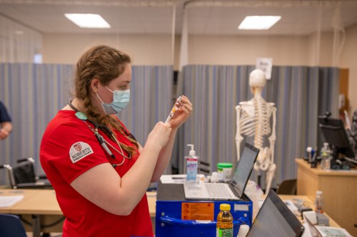 A nursing student fills vial