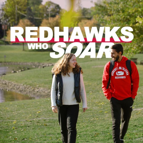 2 students walk outside on campus. The words Redhawks Who Soar.