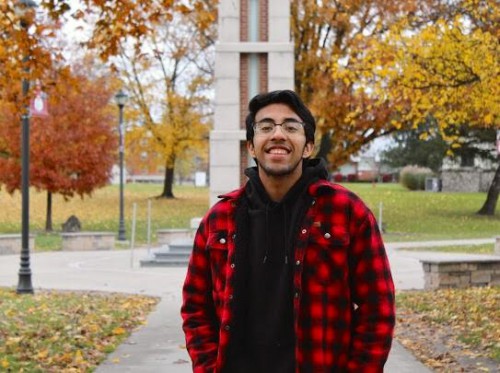 Shoun smiles in front of the clock tower on campus.